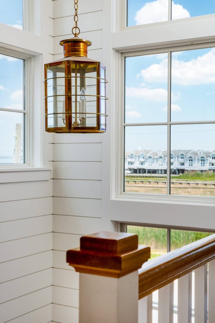 A room with two windows and a wooden shelf.