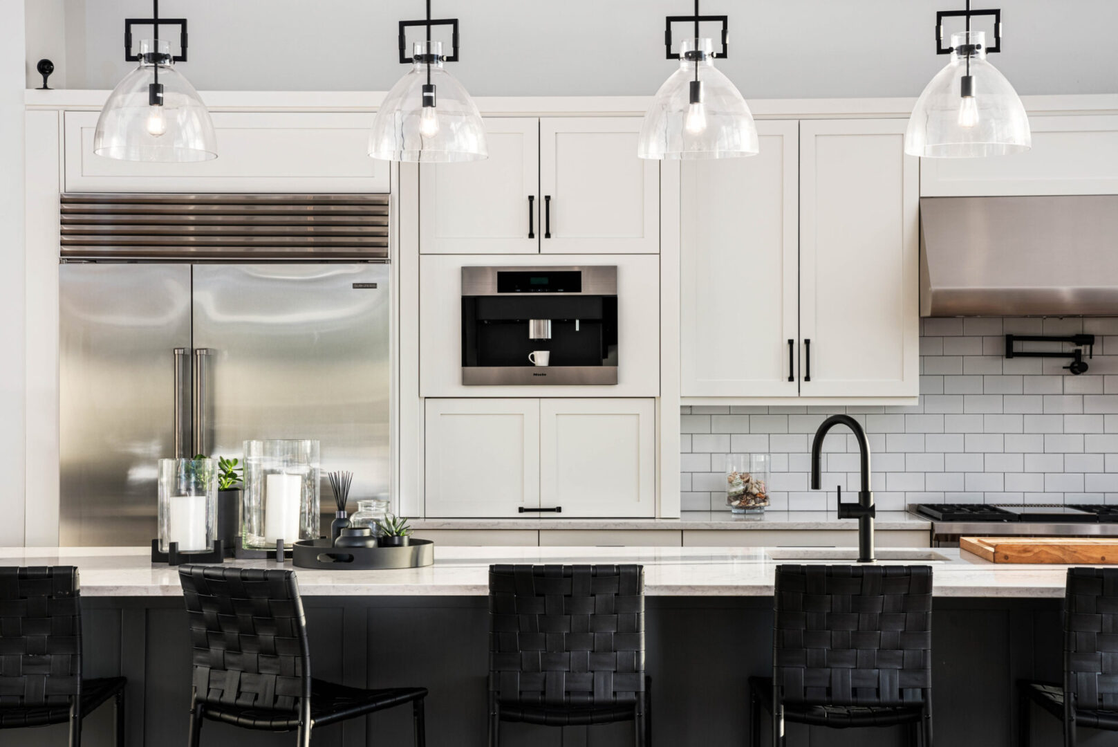 A kitchen with white cabinets and black chairs