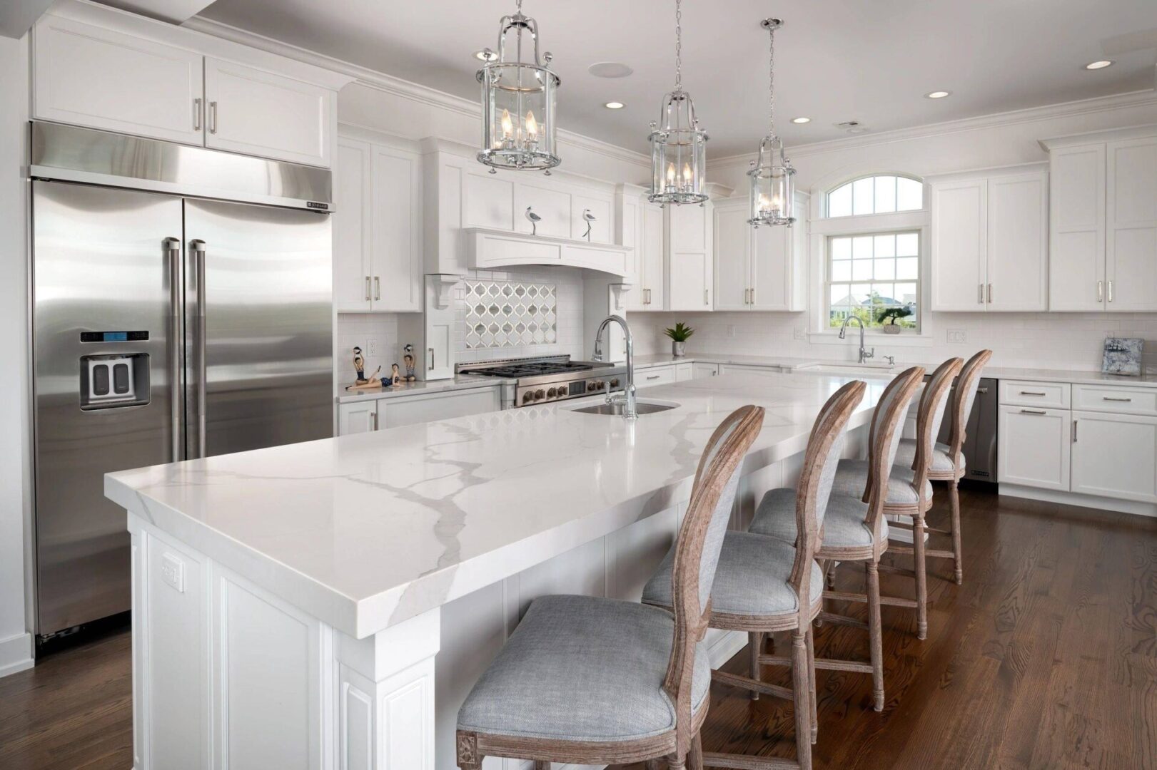 A large kitchen with white cabinets and marble counter tops.