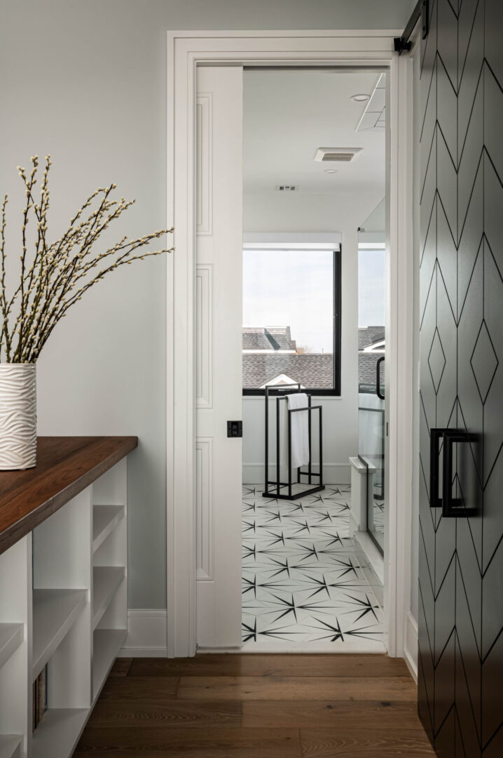 A hallway with a vase of flowers and a window.