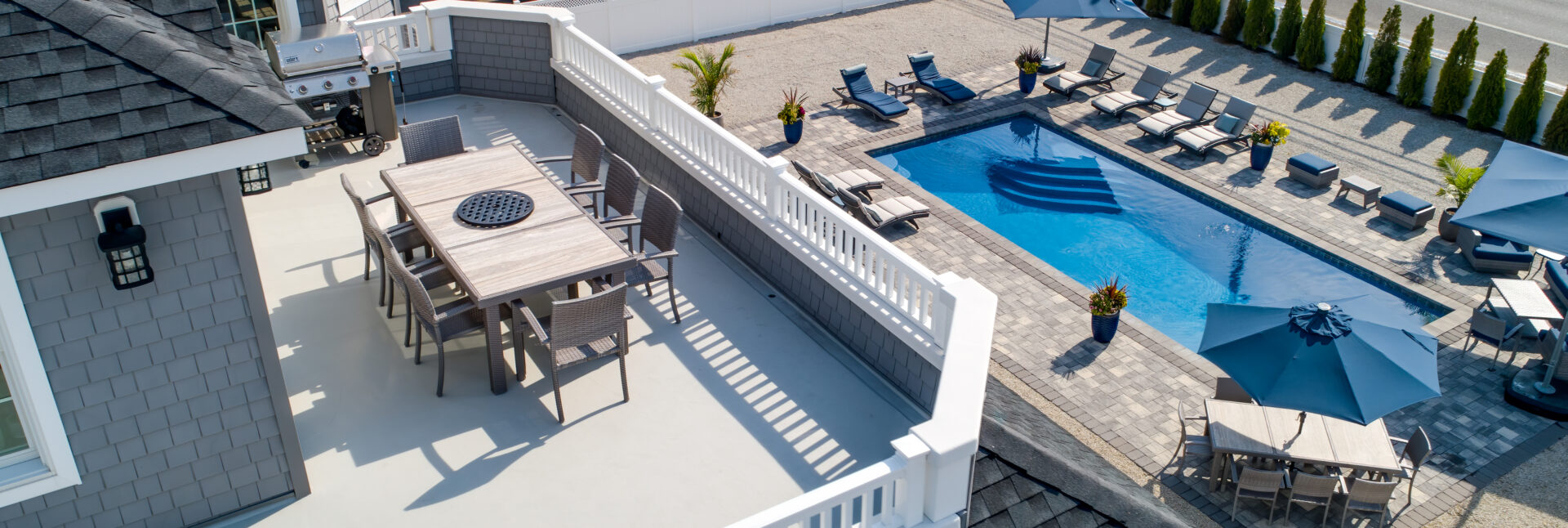 A patio with chairs and tables next to the pool.