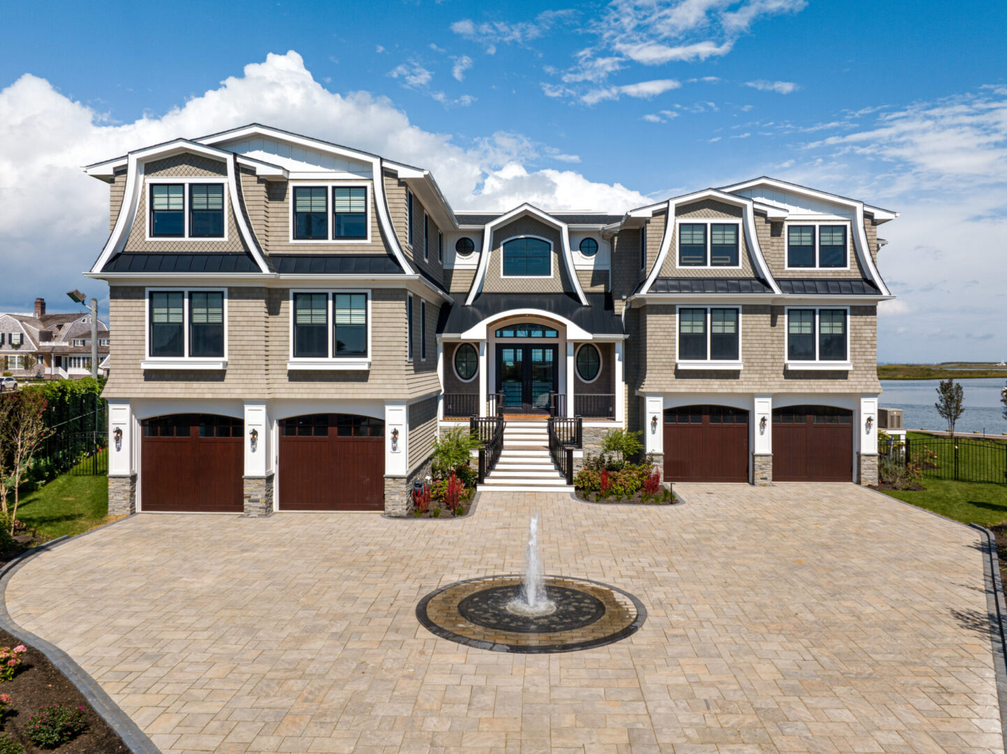 A large house with two garages and a fountain.