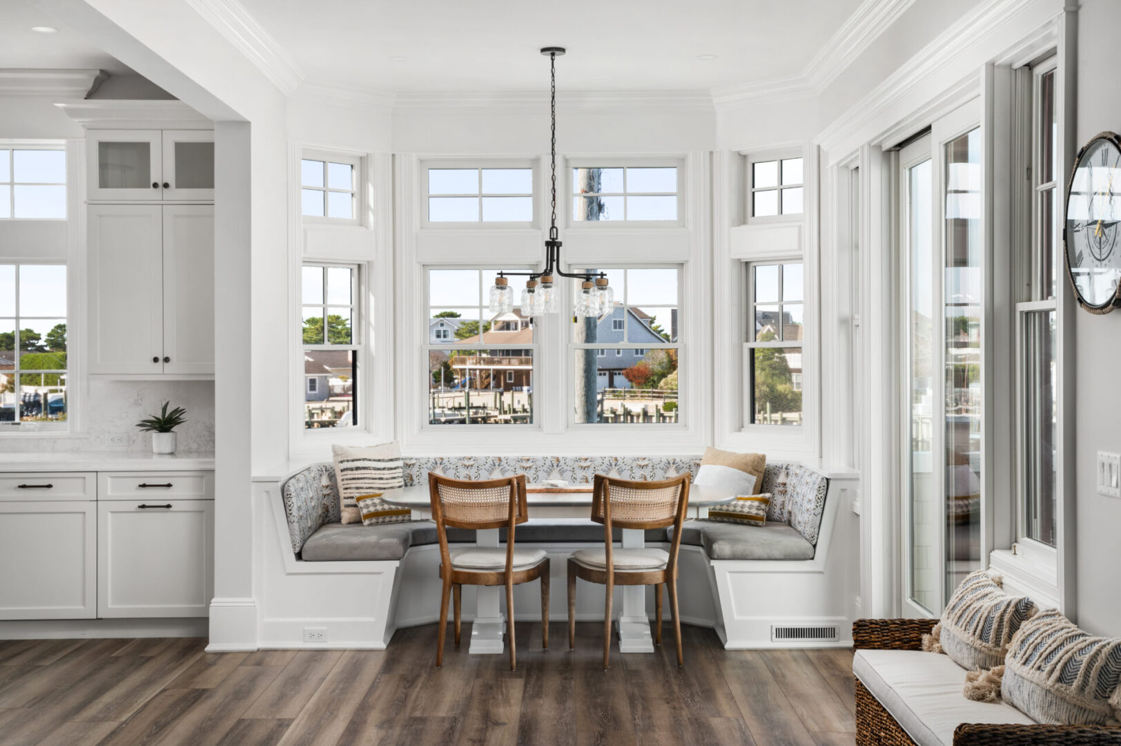 A dining room with a bench and chairs in front of the window.