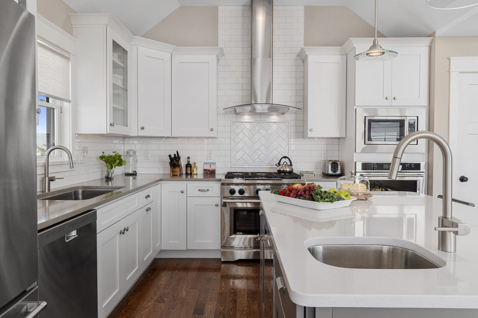 A kitchen with white cabinets and wood floors.