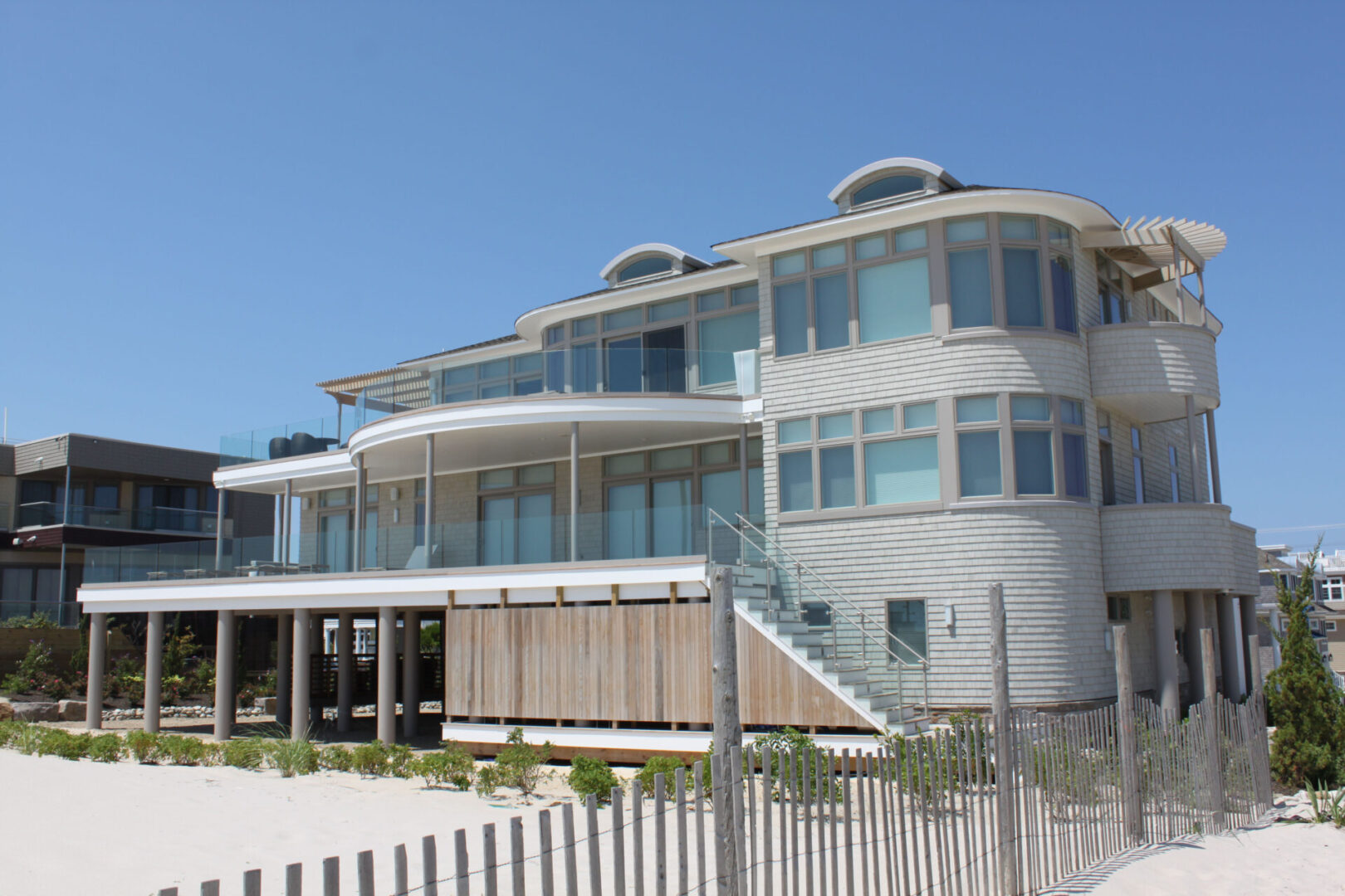 A large white building with many windows on the beach.